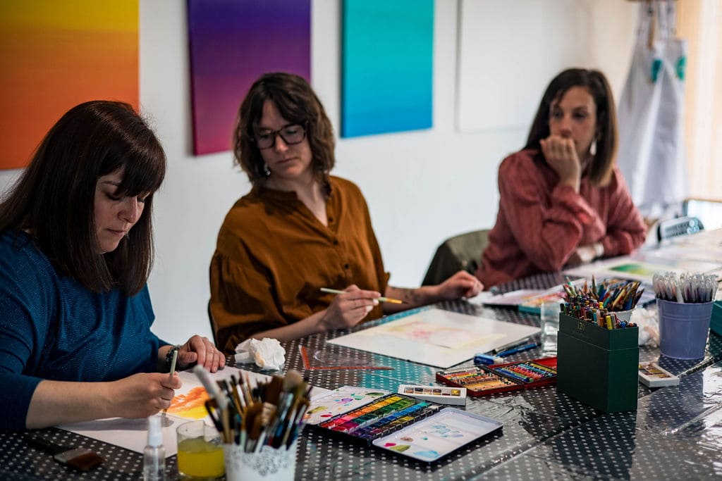 le groupe Créactive autour de la table qui regarde thérèse -marie entrain de montre un dessin