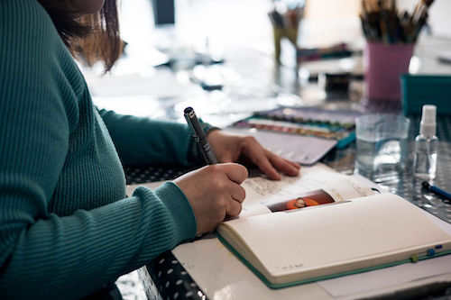 des mains qui tiennent un pinceaux et dessiner dans un carnet