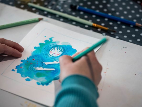Mains en train de créer une illustration dans un univers artistique coloré